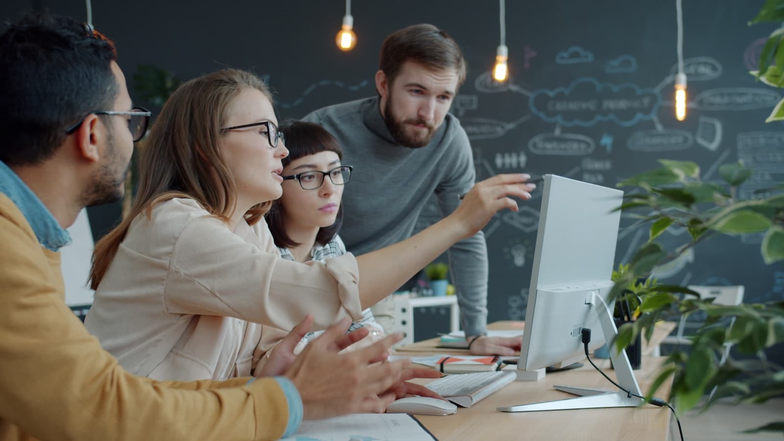 Team collaborating around a computer with strategy diagrams in the background