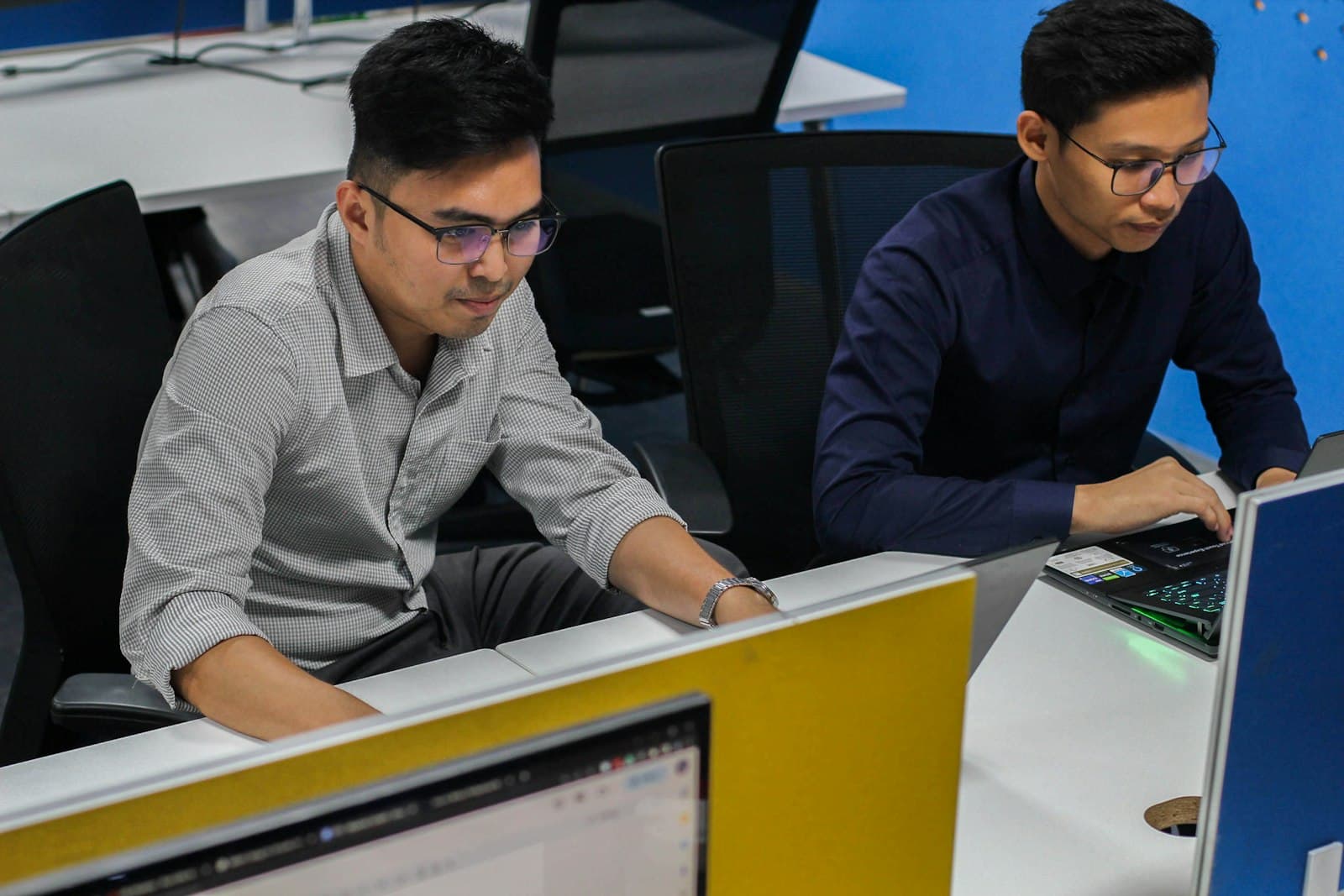 Two IT professionals working at computer workstations in a modern office